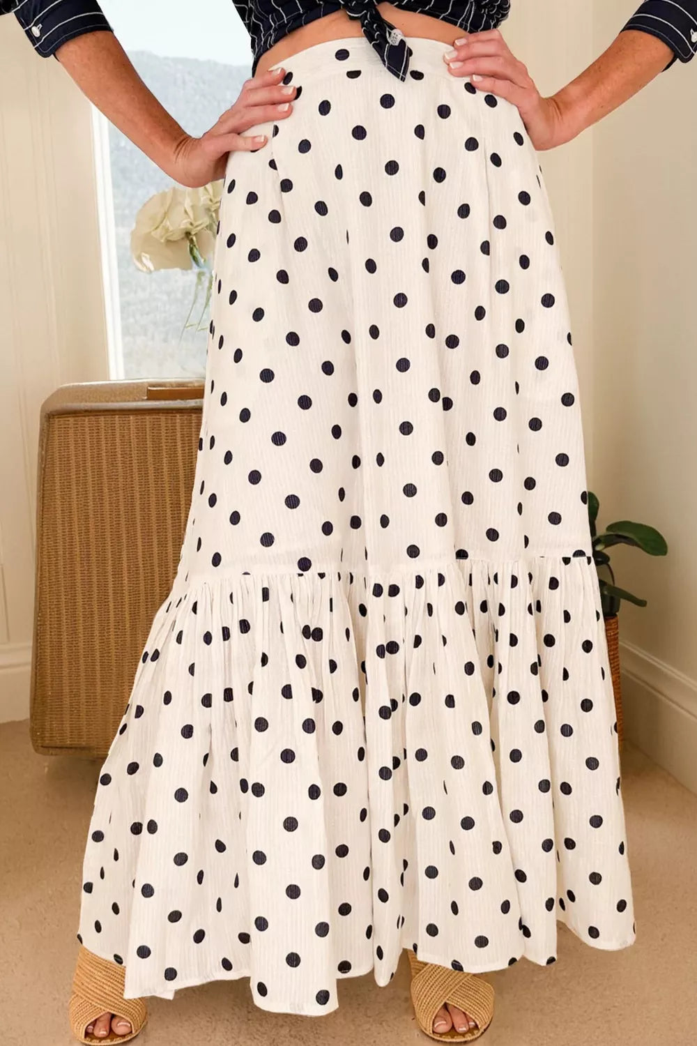 Person wearing a white polka dot skirt with a neutral background