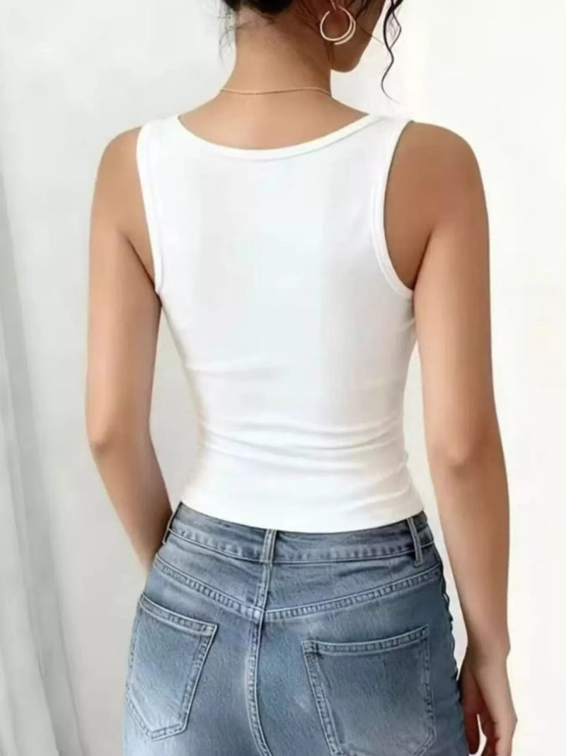Person wearing a white tank top and blue jeans on a plain background