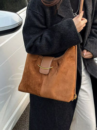 Person holding a brown handbag next to a white car