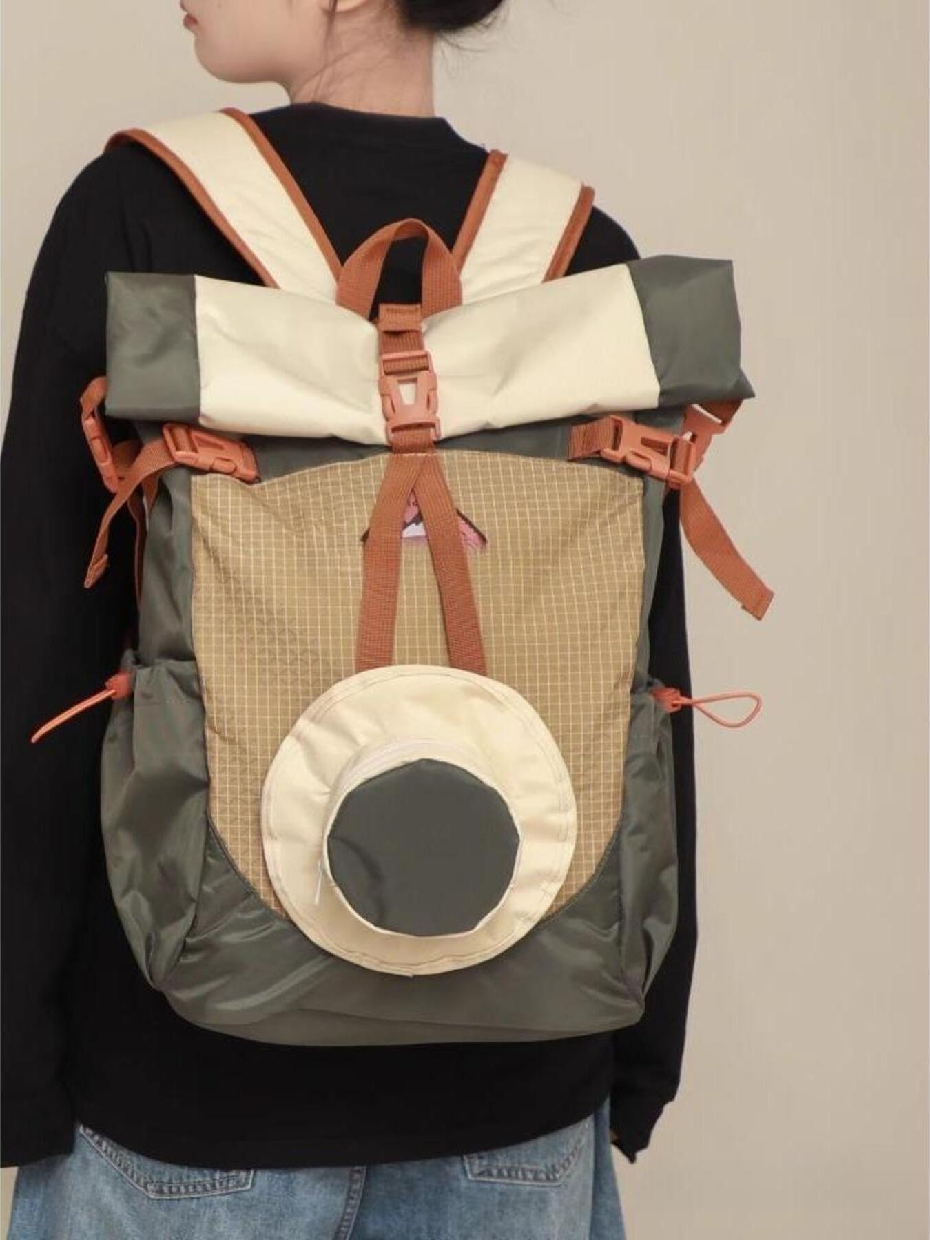 Person wearing a multi-colored backpack with a neutral background