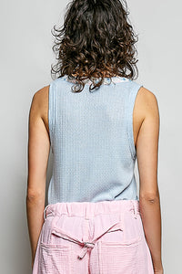 Person wearing a light blue sleeveless top and pink pants on a gray background