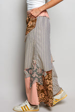 Person wearing a patchwork skirt with various patterns and colors on a plain background