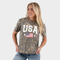 Woman wearing a camouflage t-shirt with 'USA' and an American flag design on a plain background