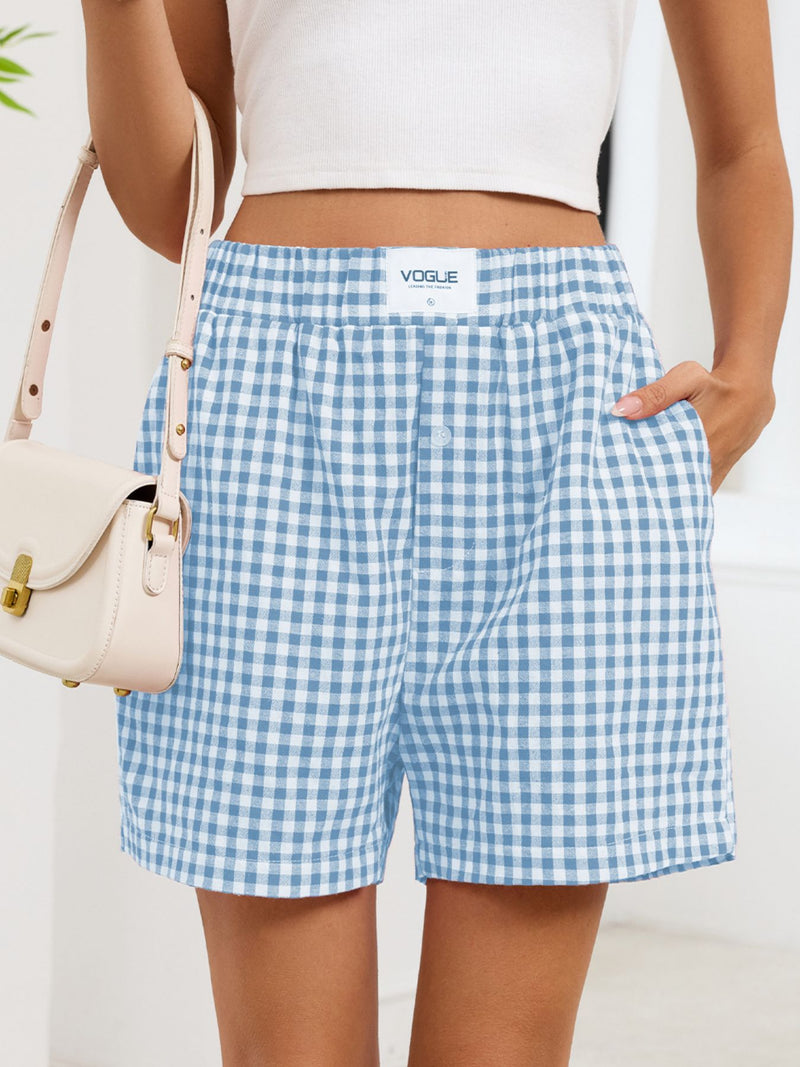 Person wearing blue and white checkered shorts with a beige handbag on a light background