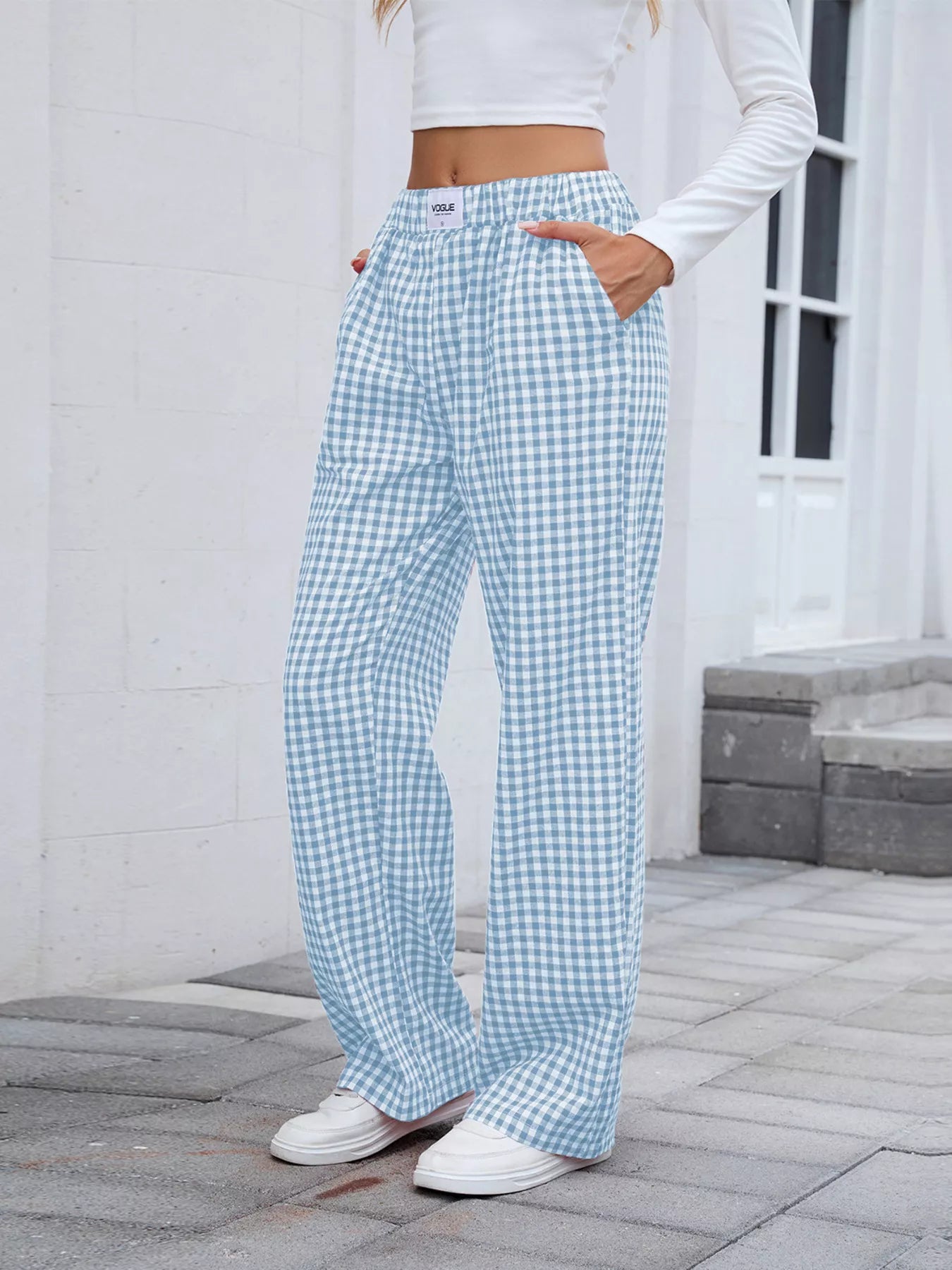 Person wearing light blue and white checkered pants with a white top outdoors.