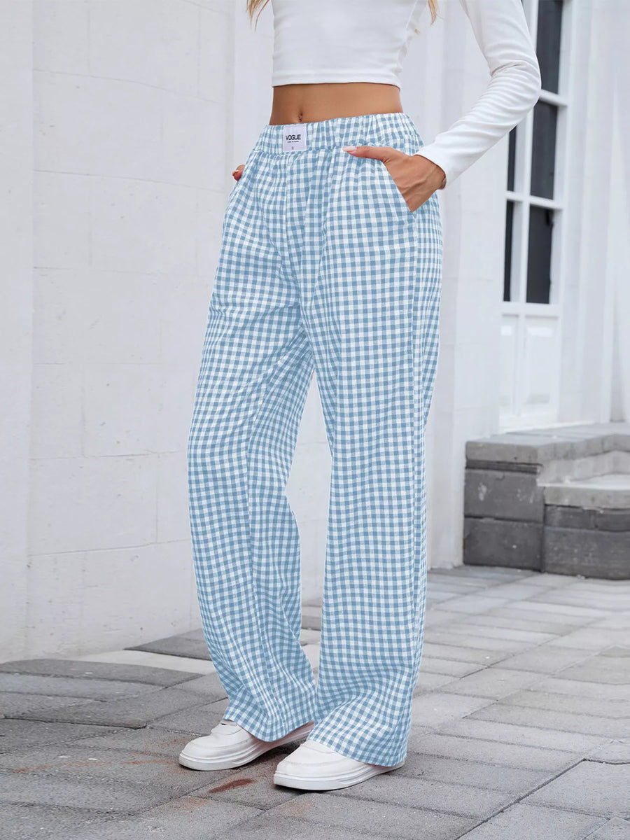 Person wearing light blue and white checkered pants with a white top outdoors.