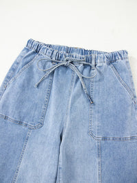 Light blue denim pants with a drawstring waist on a white background