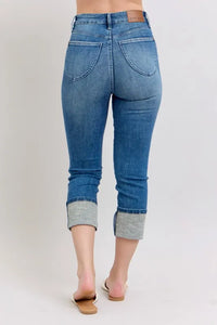 Blue jeans with rolled-up cuffs on a plain background