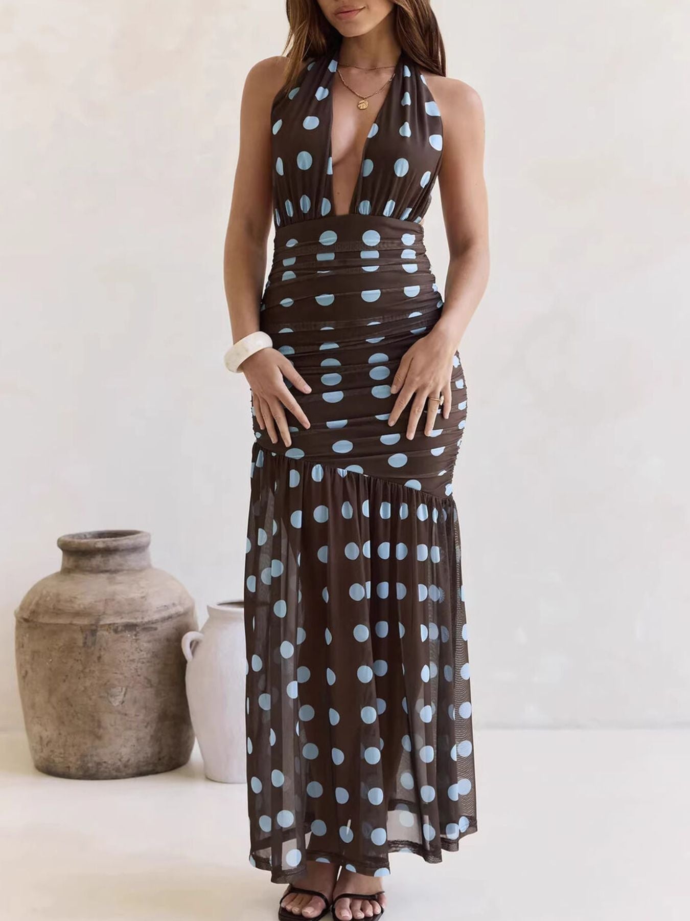 Woman wearing a brown dress with blue polka dots against a white background