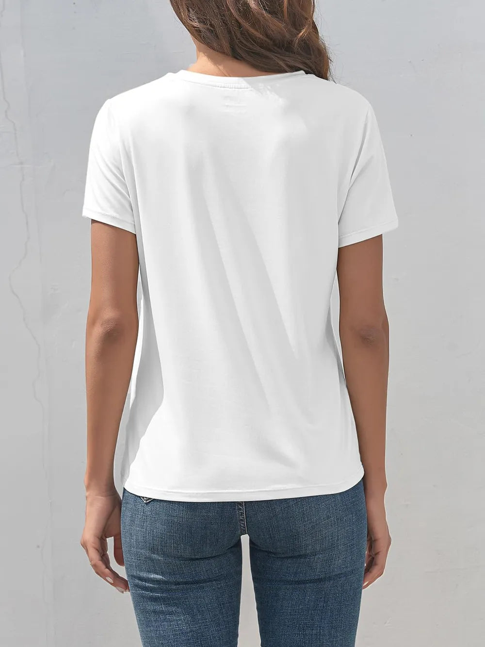 Person wearing a plain white t-shirt and blue jeans against a gray background