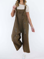 Person wearing brown distressed overalls on a white background