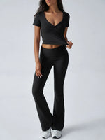 Woman wearing a black outfit with a top and flared pants on a white background