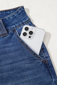 Smartphone with a white case in the pocket of blue jeans on a light gray background