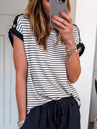 Person wearing a black and white striped shirt with navy pants, taking a mirror selfie.