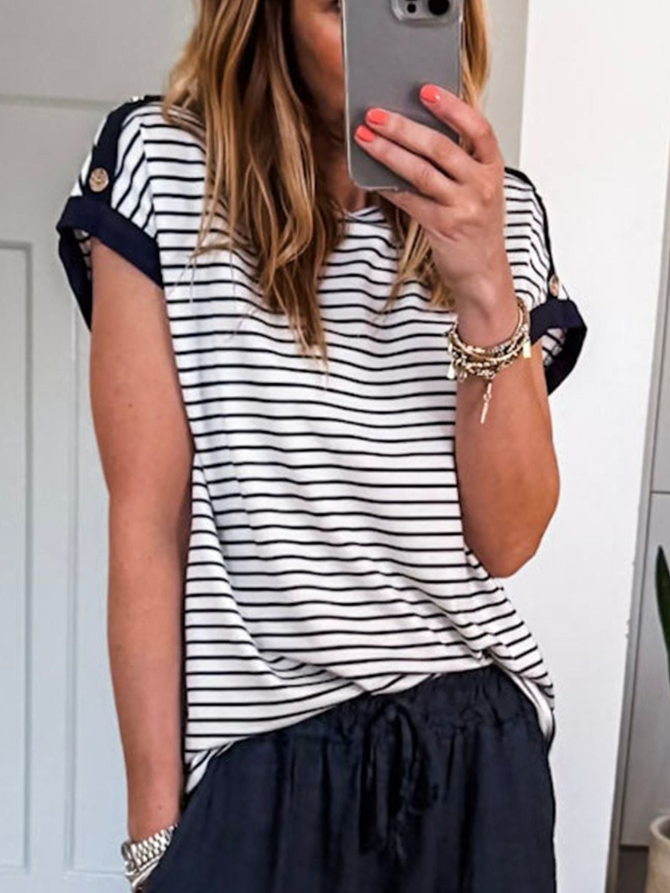 Person wearing a black and white striped shirt with navy pants, taking a mirror selfie.