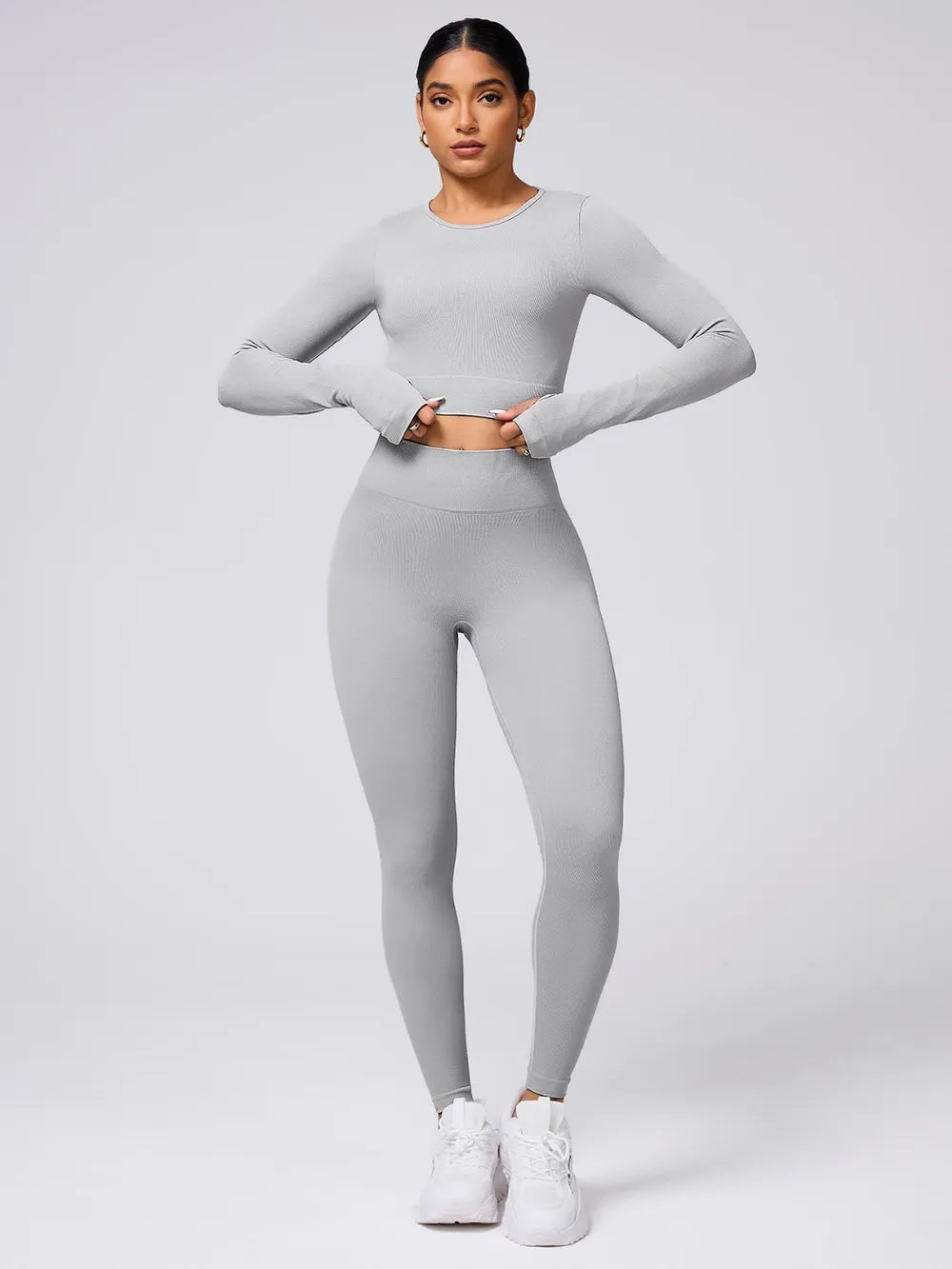 Person wearing a gray long-sleeve top and leggings set on a light gray background