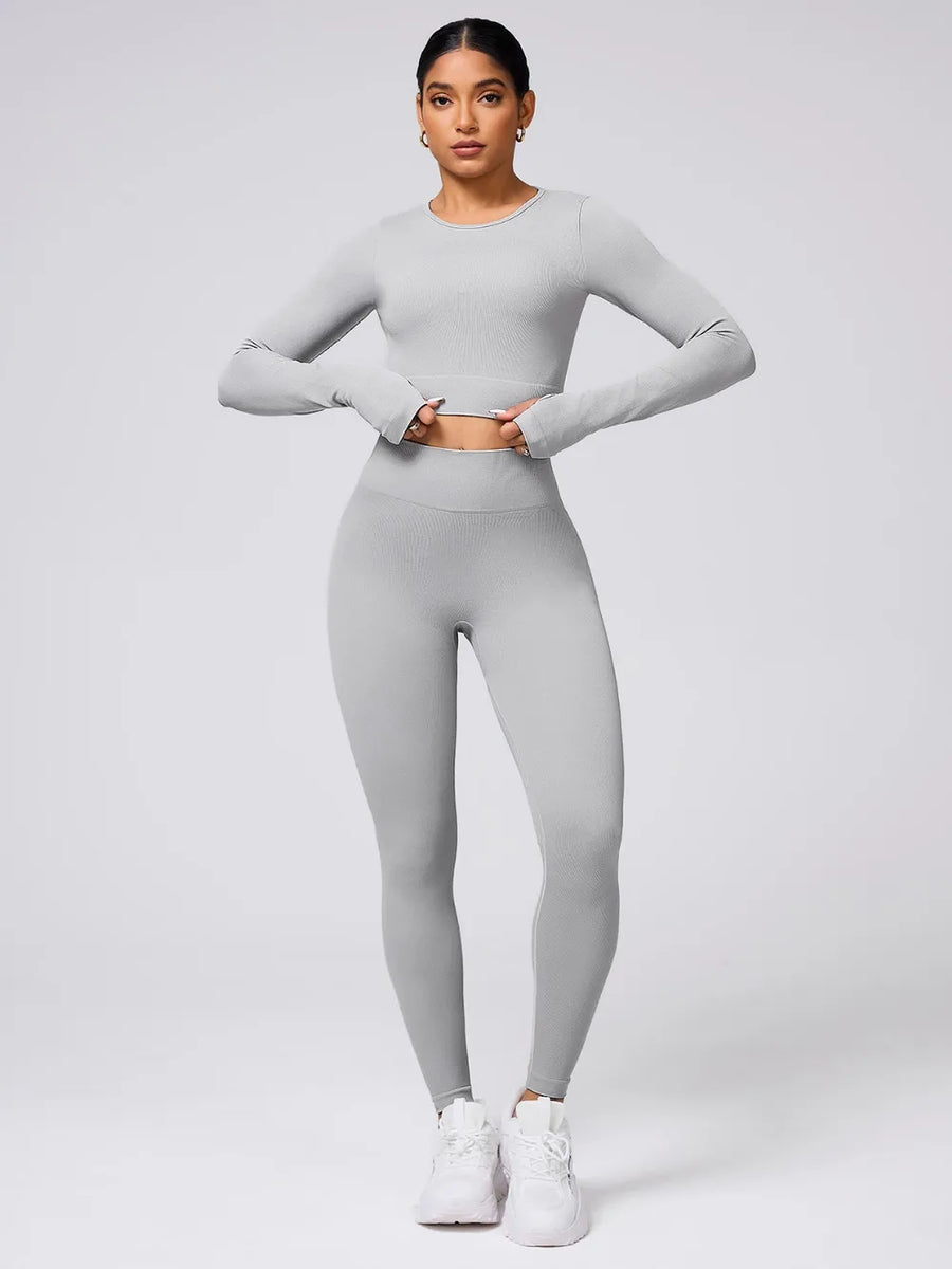 Person wearing a gray long-sleeve top and leggings set on a light gray background