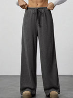 Person wearing gray wide-leg pants with a plain background