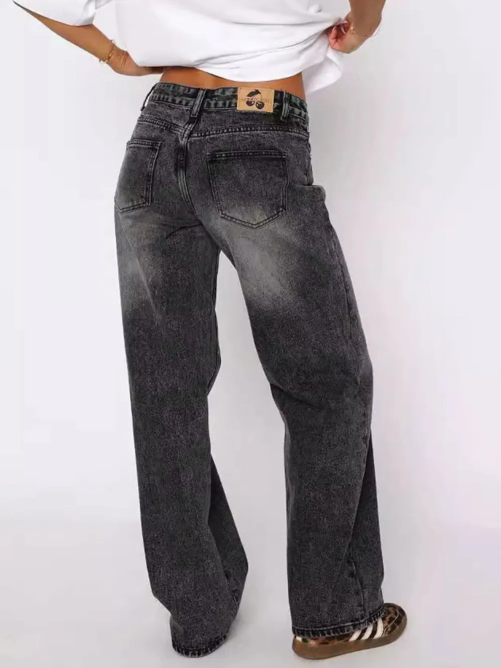 Person wearing black acid-wash jeans on a white background