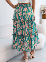 Person wearing a green floral skirt sitting on a white couch.