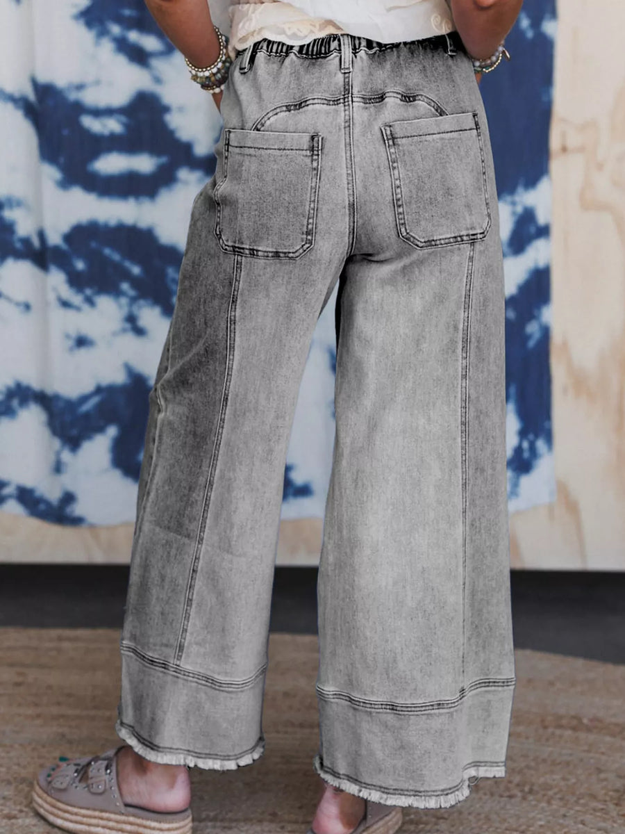 Person wearing wide-leg gray jeans with a tie-dye background