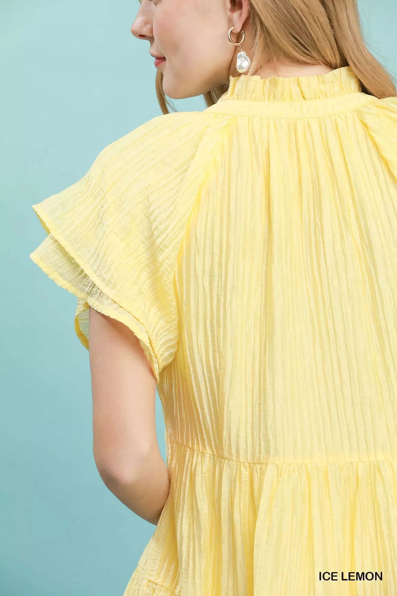 Yellow pleated dress with ruffled sleeves on a light blue background
