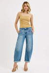 Woman wearing a beige tank top and blue jeans on a white background