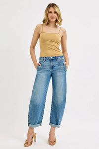 Woman wearing a beige tank top and blue jeans on a white background