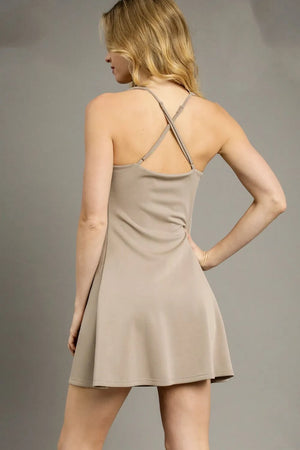 Woman wearing a beige dress against a gray background