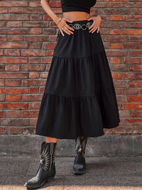 Person wearing a black tiered skirt and cowboy boots against a brick wall.