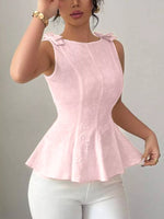 Woman wearing a pink sleeveless top with a bow detail on a plain background