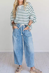 Person wearing a striped shirt and blue jeans with a white background