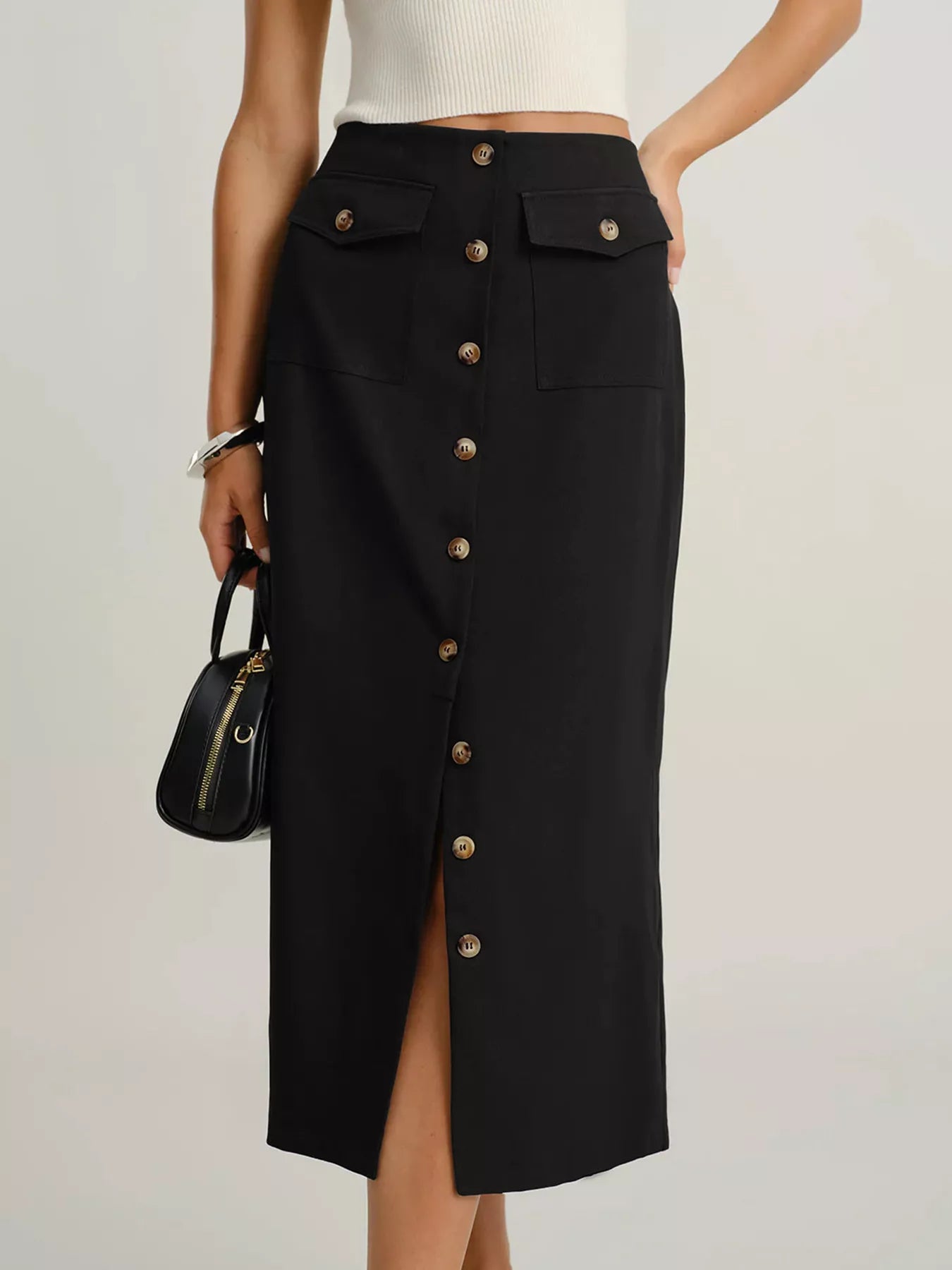 Person wearing a black button-up skirt with a white top on a light gray background