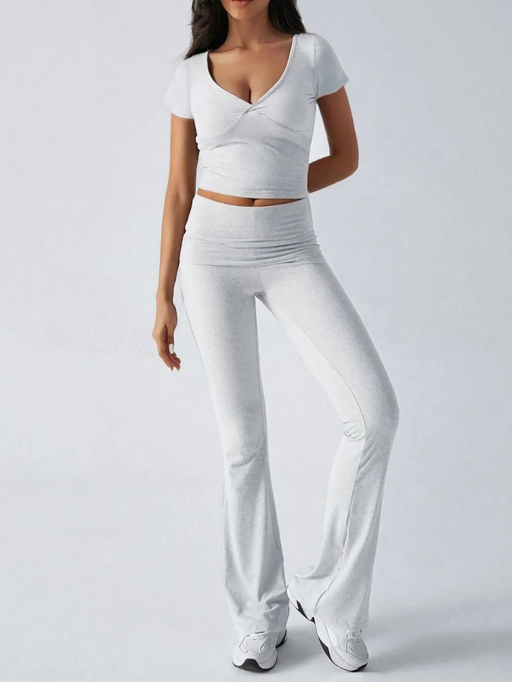Person wearing a white outfit with a top and wide-leg pants on a plain background