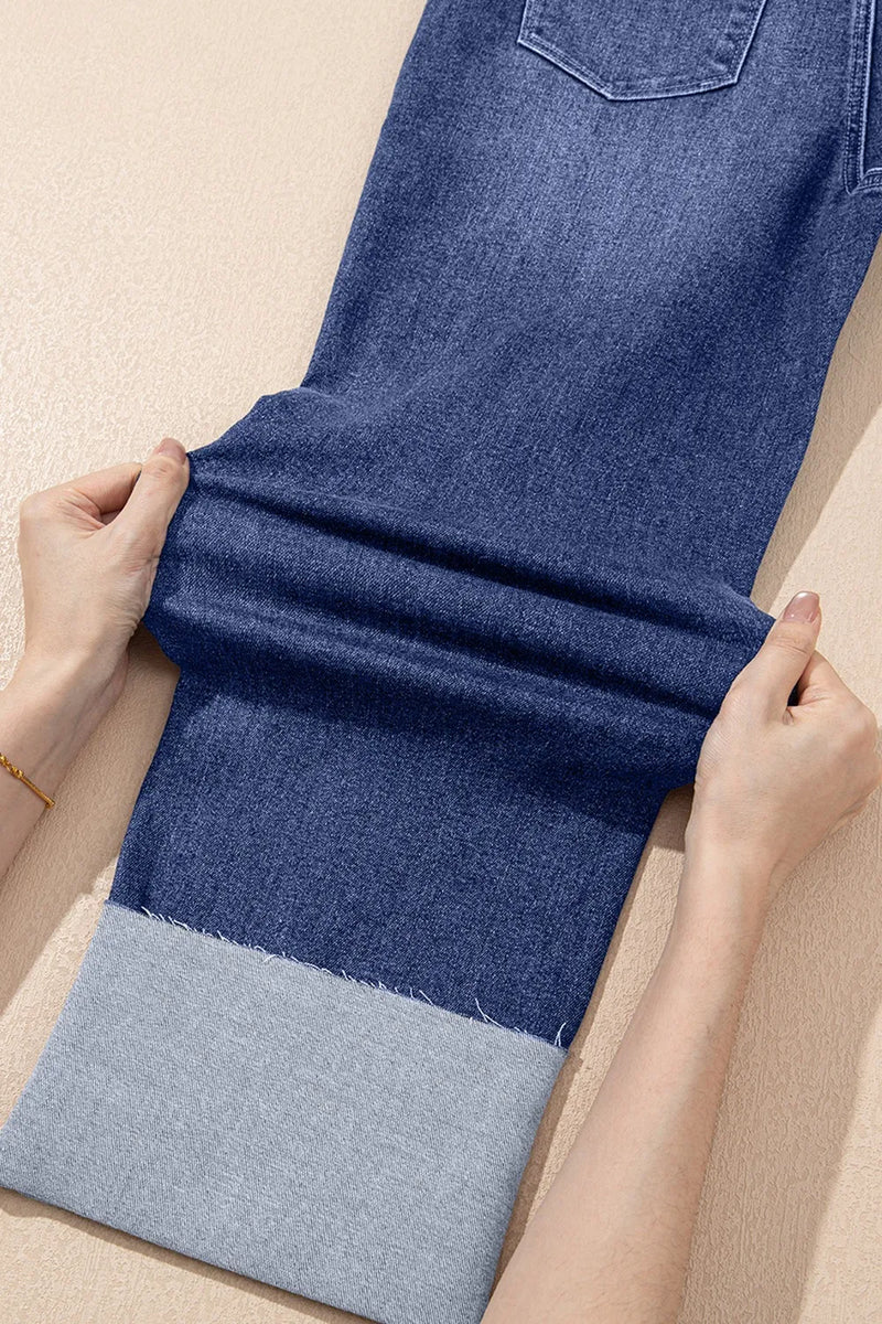 Person folding a blue denim fabric on a beige surface