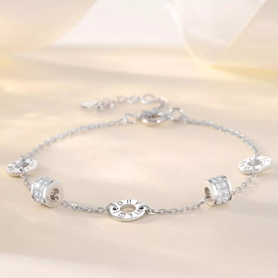 Silver bracelet with various charms on a light background