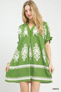 Woman wearing a green dress with white patterns on a white background