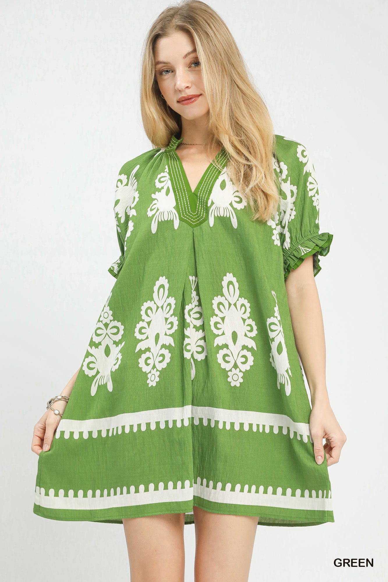 Woman wearing a green dress with white patterns on a white background