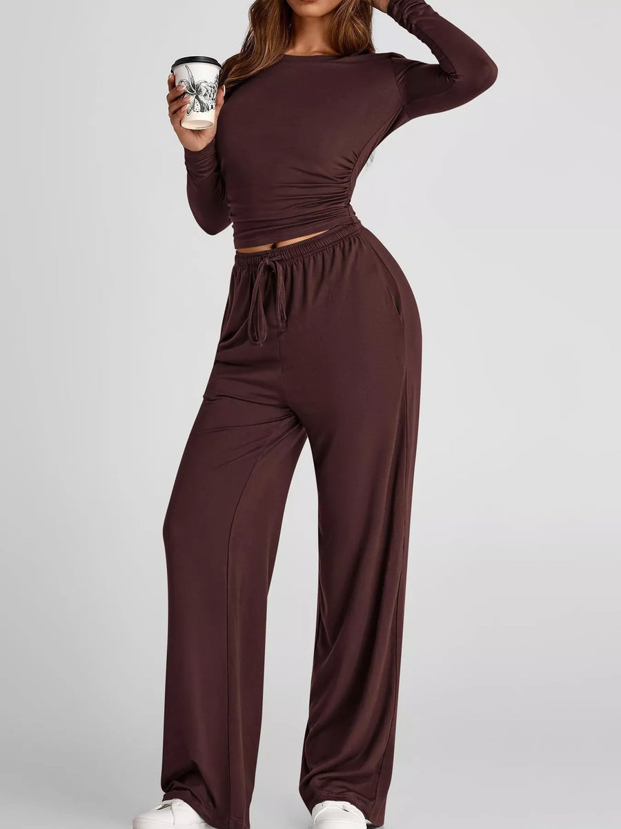 Person wearing a brown outfit holding a coffee cup on a light gray background