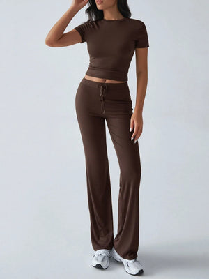 Woman wearing a brown outfit with a top and wide-leg pants on a light gray background