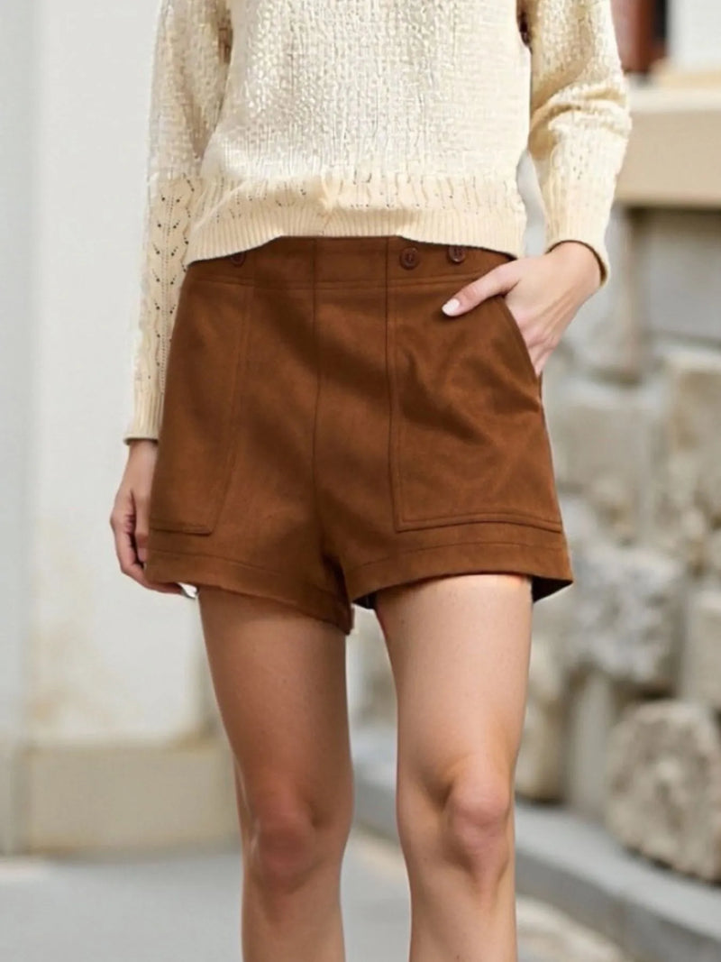 Person wearing brown shorts and a beige sweater in an outdoor setting