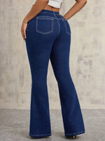 Blue flared jeans worn by a person against a gray concrete wall.