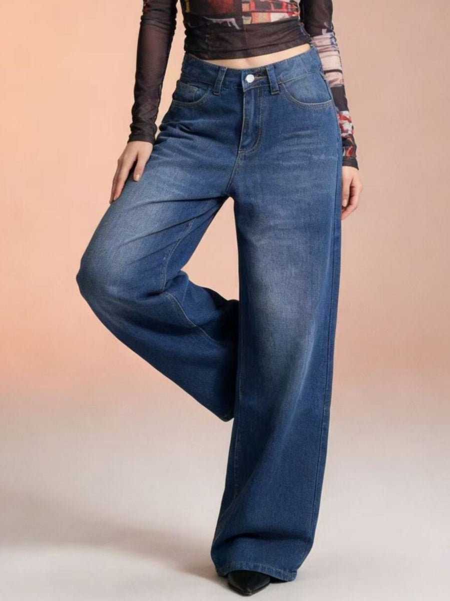 Person wearing blue wide-leg jeans on a beige background