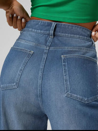 Close-up of blue jeans being adjusted by hands against a neutral background