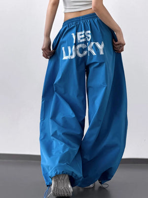 Blue pants with 'YES LUCKY' text worn by a person on a plain background