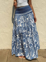 Person wearing a blue and white patterned skirt against a beige wall.