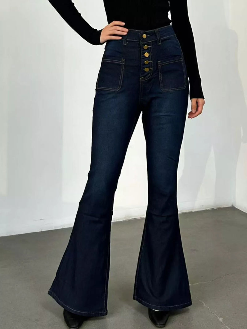 Person wearing dark blue flared jeans with a white background