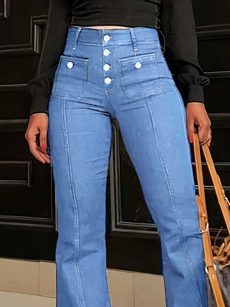 Person wearing blue jeans with button details against a black background