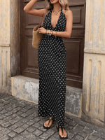 Woman wearing a navy blue dress with white polka dots standing in front of a stone building.