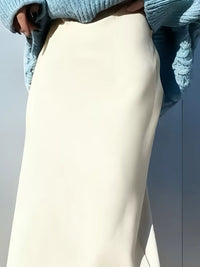 Close-up of a person wearing light-colored pants and a blue sweater with a textured pattern.